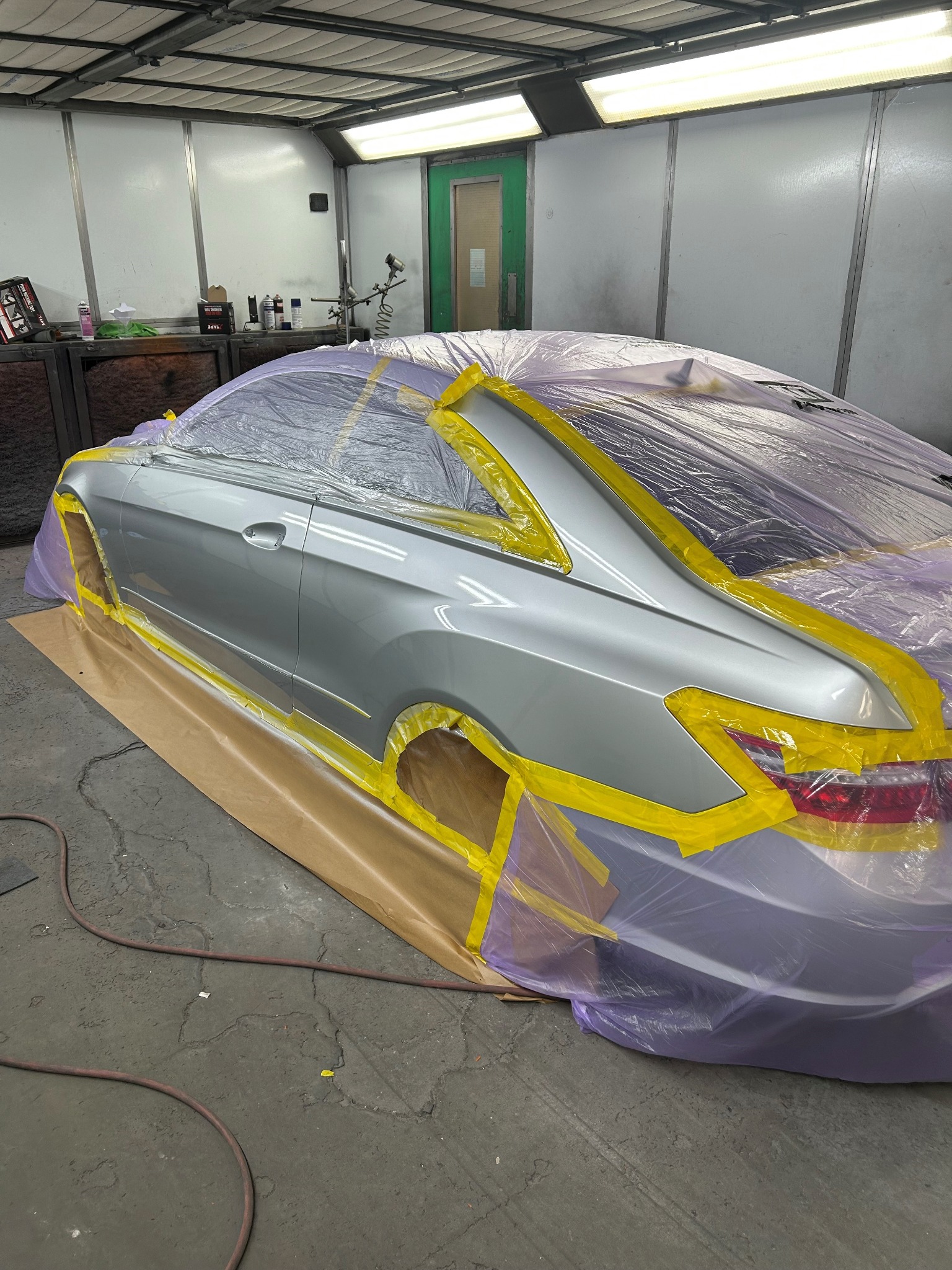 Silver vehicle prepared and masked for refinishing in the spray booth